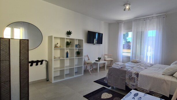 A bedroom with a bed, a TV, a wardrobe, a desk, and a chair. - Apartments Pleasures (Jelsa)