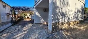 A cobblestone street leading to a building with a stone facade and a small entrance. - Apartments Pleasures (Jelsa)