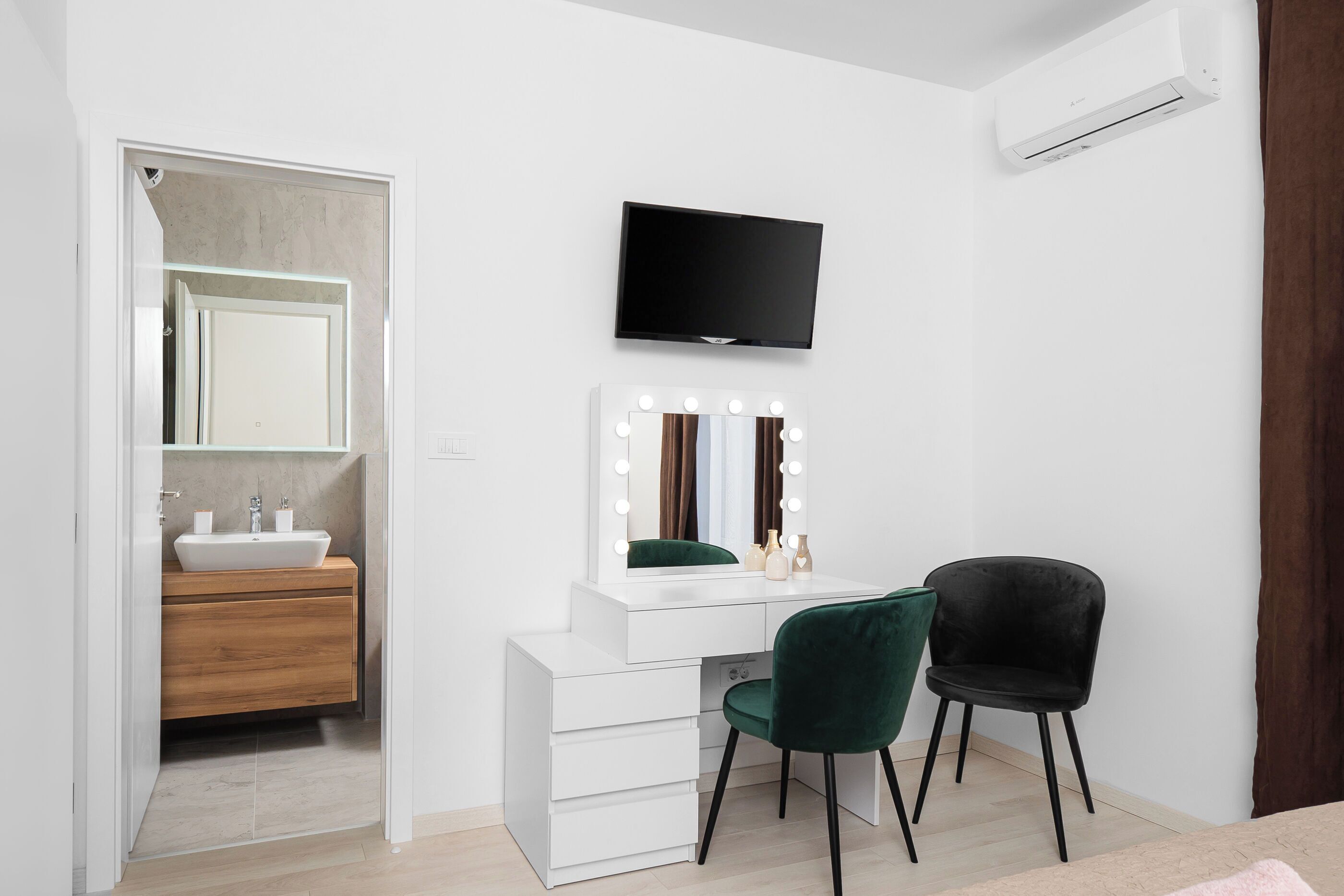 A modern bathroom with a vanity, mirror, and two chairs.