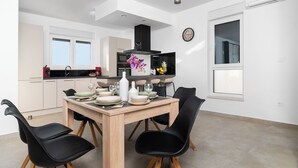 Une cuisine moderne avec une table à manger pour quatre personnes, agrémentée de chaises noires aux pieds en bois.
