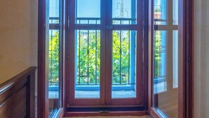 Ein Zimmer mit Holzboden, einem großen Fenster mit Holzrahmen und Blick ins Grüne.