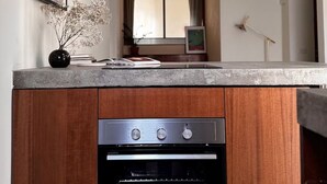 A compact kitchen with a built-in oven and a countertop. - Botanical modernist home | Milanese living (Milano)