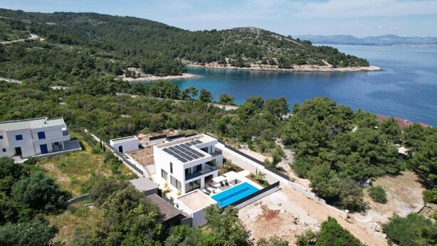 Una casa moderna con piscina, rodeada de exuberante vegetación y vista al mar.