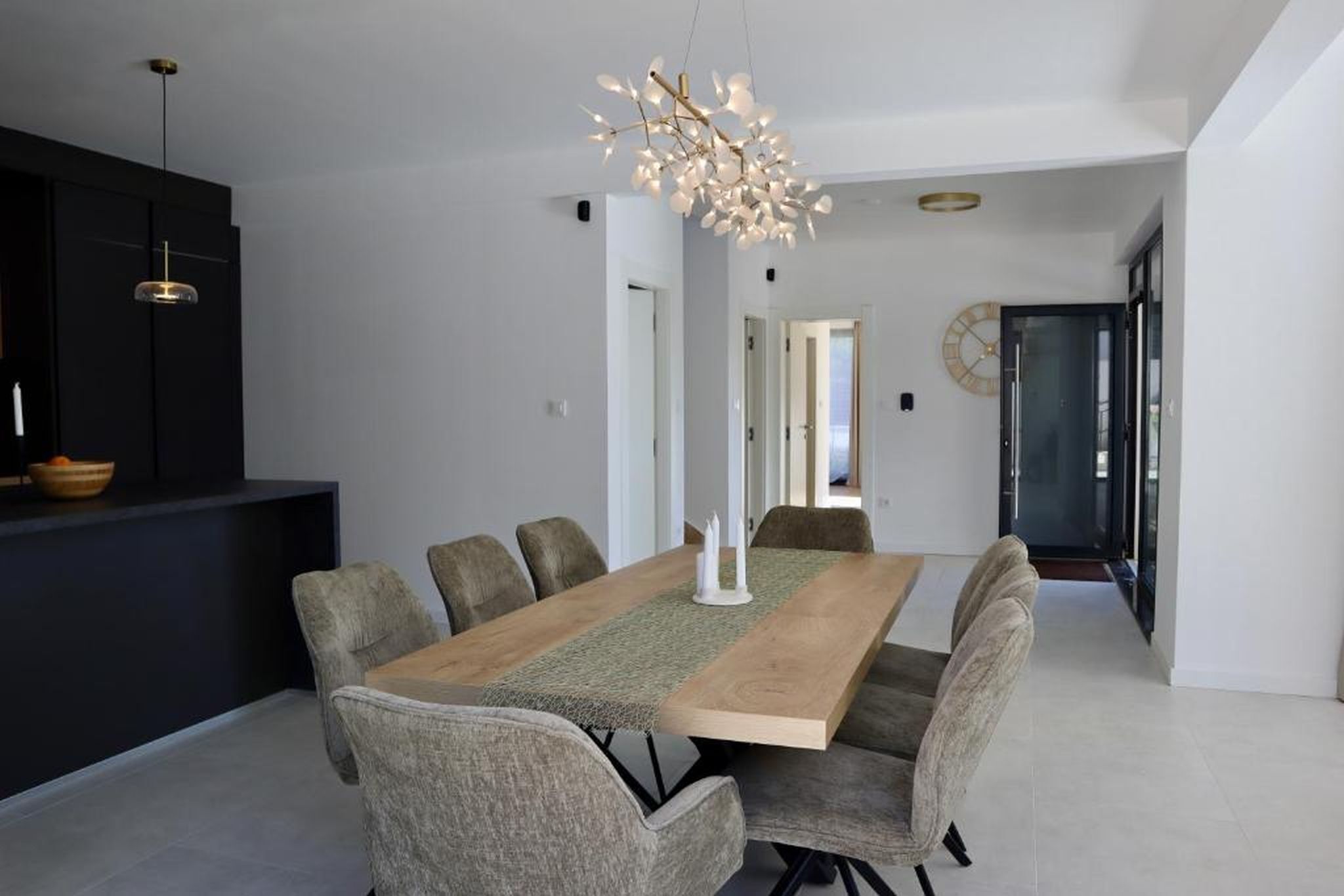 Uma sala de jantar moderna com uma mesa de madeira, cadeiras estofadas e um candelabro exclusivo.