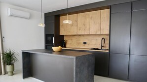 Una cocina moderna con una isla central, armarios de madera e iluminación colgante.