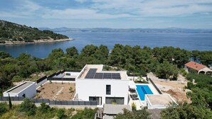 Una villa moderna con piscina en la azotea, paneles solares y vistas al mar.