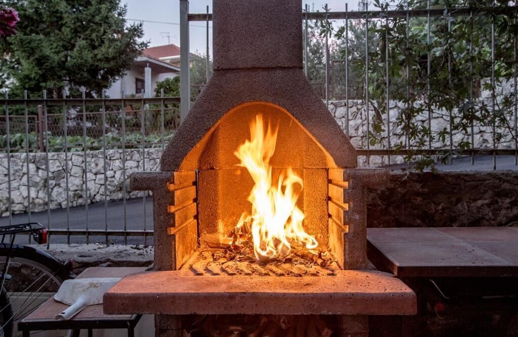 An outdoor brick pizza oven with a fire burning inside.