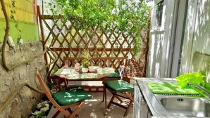 Pieni patio, jossa on pöytä ja tuoleja, pesuallas ja puinen aita.