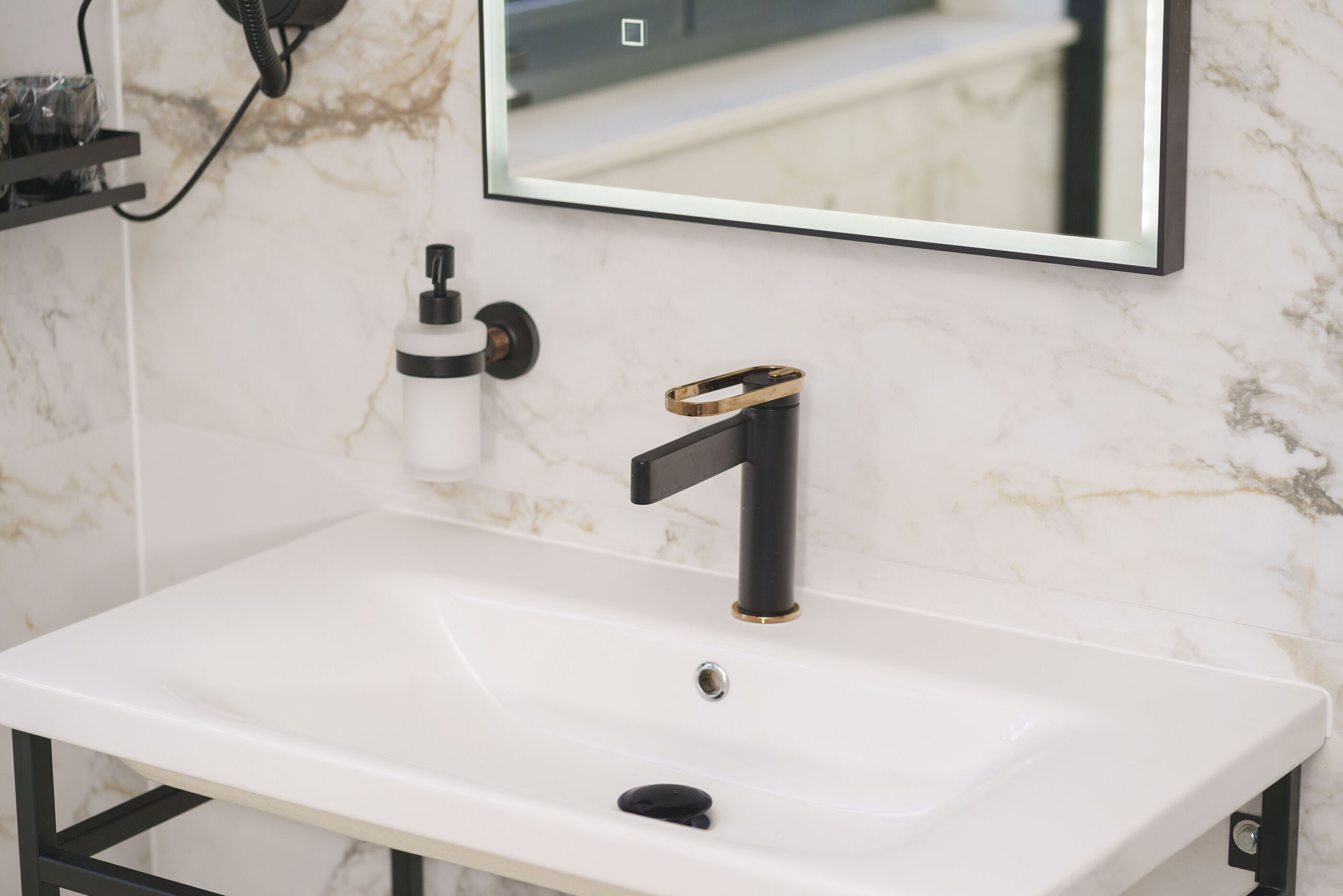 A bathroom with a white sink, black faucet, and a gold accent.