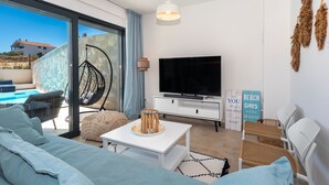 A modern living room with a large TV, comfortable seating, a hanging chair, and a view of the outside. - Villa Navy Lemon (Vodice)