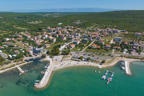 An aerial view of a coastal town with residential buildings, a marina, and a beach. - House Stratus (Sukosan)