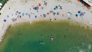 Vista aérea de una playa con gente tomando el sol y nadando.