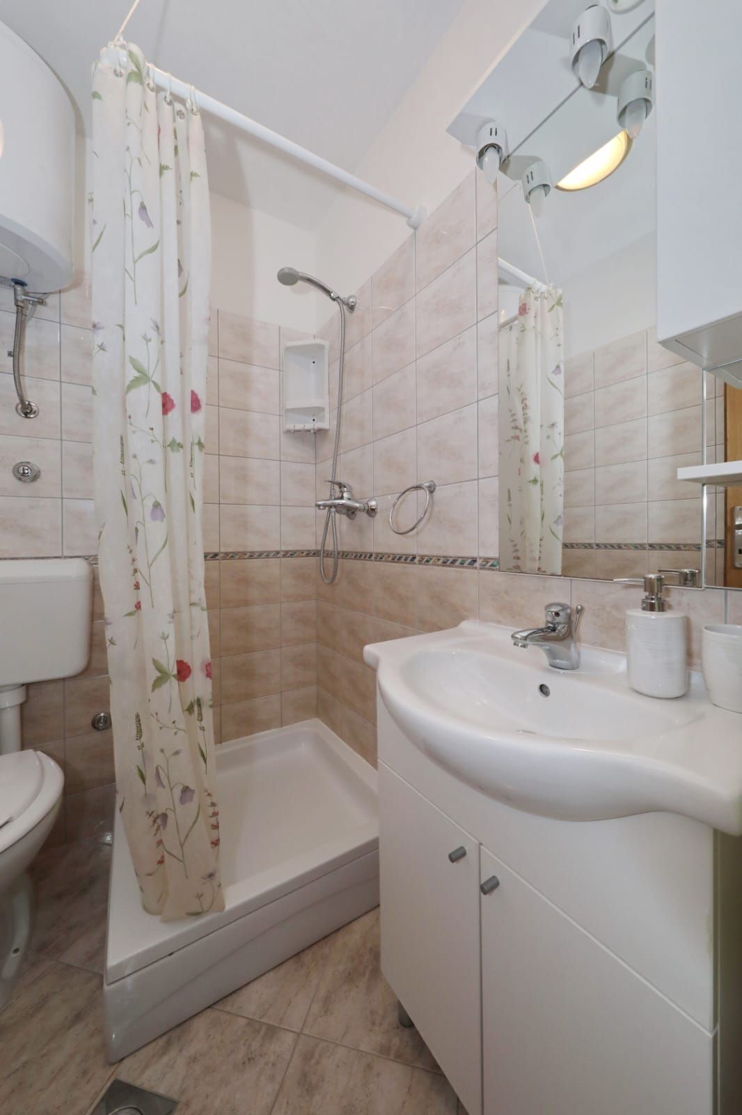 Ein Badezimmer mit Dusche, Toilette, Waschbecken und Spiegel.