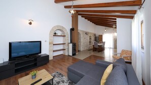 Una sala de estar moderna con un televisor de pantalla plana, un sofá, una mesa de centro de madera y una chimenea de piedra.