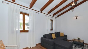 Una sala de estar con un sofá modular, una mesita y un ventanal con cortinas.