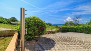 A paved outdoor area with a metal structure, a hedge, and a view of the sea. - Apartment Ereiz (Crikvenica)