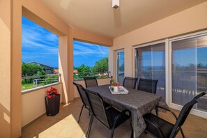 Un balcon avec une table et des chaises, un pot de fleurs et une vue sur des immeubles et des arbres.