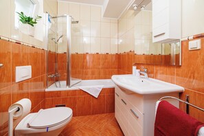 Une salle de bain avec une douche à parois de verre, un lavabo blanc et des toilettes.