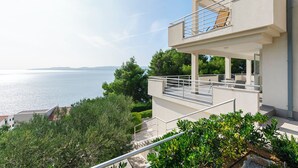 A modern two-story building with a balcony overlooking a body of water. - Apartments Olive sea View (Omis)