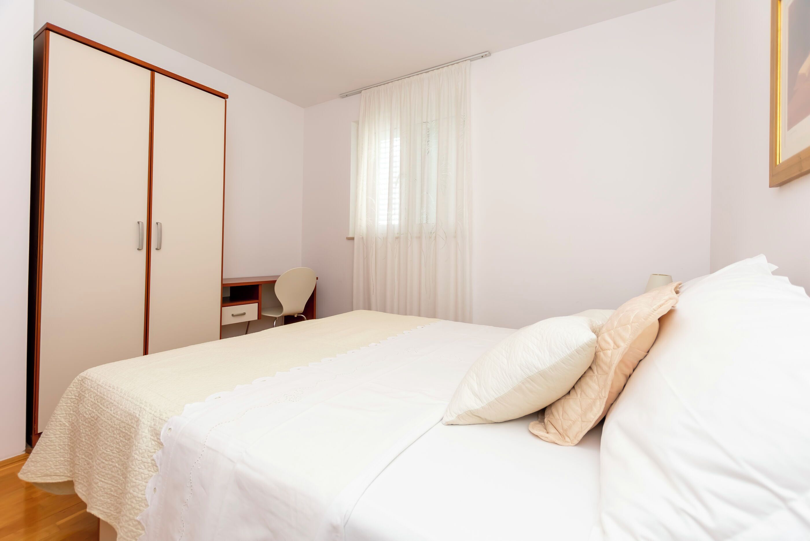 Un dormitorio con cama, armario, escritorio y silla.