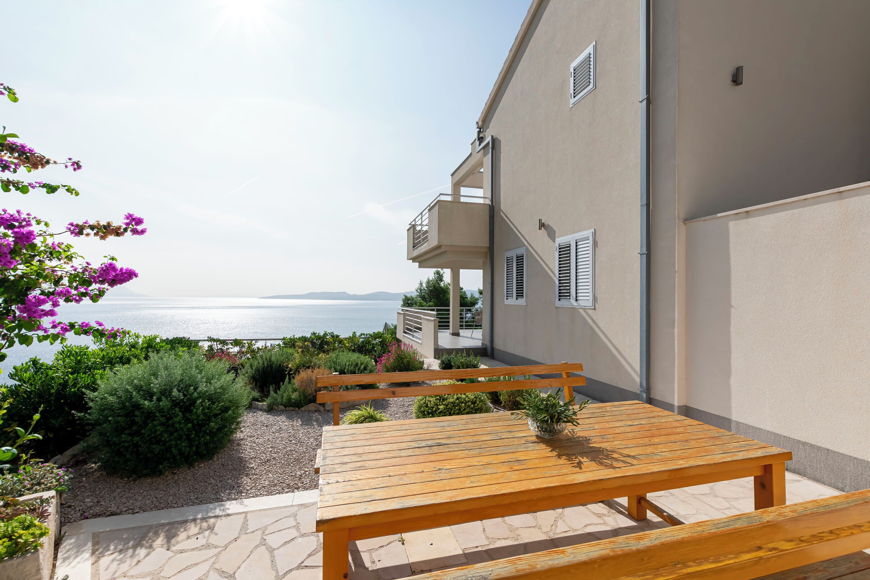 Un tavolo e una panca di legno su una terrazza con vista sul mare.