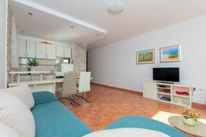 Un salon moderne comprenant un canapé, un coin repas, une cuisine et un téléviseur.
