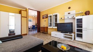A living room with a sofa, TV, and cabinets. There is a dining area in the background. - Apartment Serda (Preko)