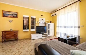 A room with a TV, white shelving, a wooden dresser, and a bed. - Apartment Serda (Preko)