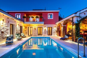 A two-story house with a swimming pool, stone walls, and outdoor seating. - Villa Pamaroka (Sibenik)