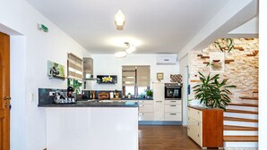 A modern kitchen with a central island, built-in appliances, and a stone accent wall. - Villa Pamaroka (Sibenik)