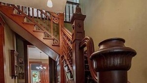 A grand staircase with wooden railings and a decorative column, leading to a second floor. - Bricks & Chance Luxury 5 BR home, NEAR Benedictine (Atchison)