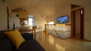Ein Wohnzimmer mit einer Couch und einem an der Wand montierten Fernseher.