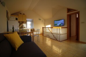 Ein Wohnzimmer mit einer Couch und einem an der Wand montierten Fernseher.