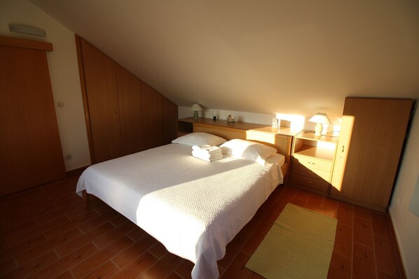 Une chambre à coucher comprenant un lit, des tables de chevet, une commode, une lampe et une armoire.