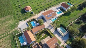 An aerial view of a residential area with multiple houses, each featuring a swimming pool and a garden. - House Stone Curlew 2 (Benkovac)