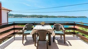 A terrace with a table and chairs, overlooking a coastal view. - Apartments Luci (Rab)