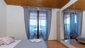 A bedroom with a large bed, a mirror, and sheer curtains. - Apartments Luci (Rab)