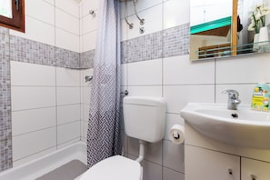 A bathroom with a shower, toilet, sink, and a mirror. - Apartments Luci (Rab)
