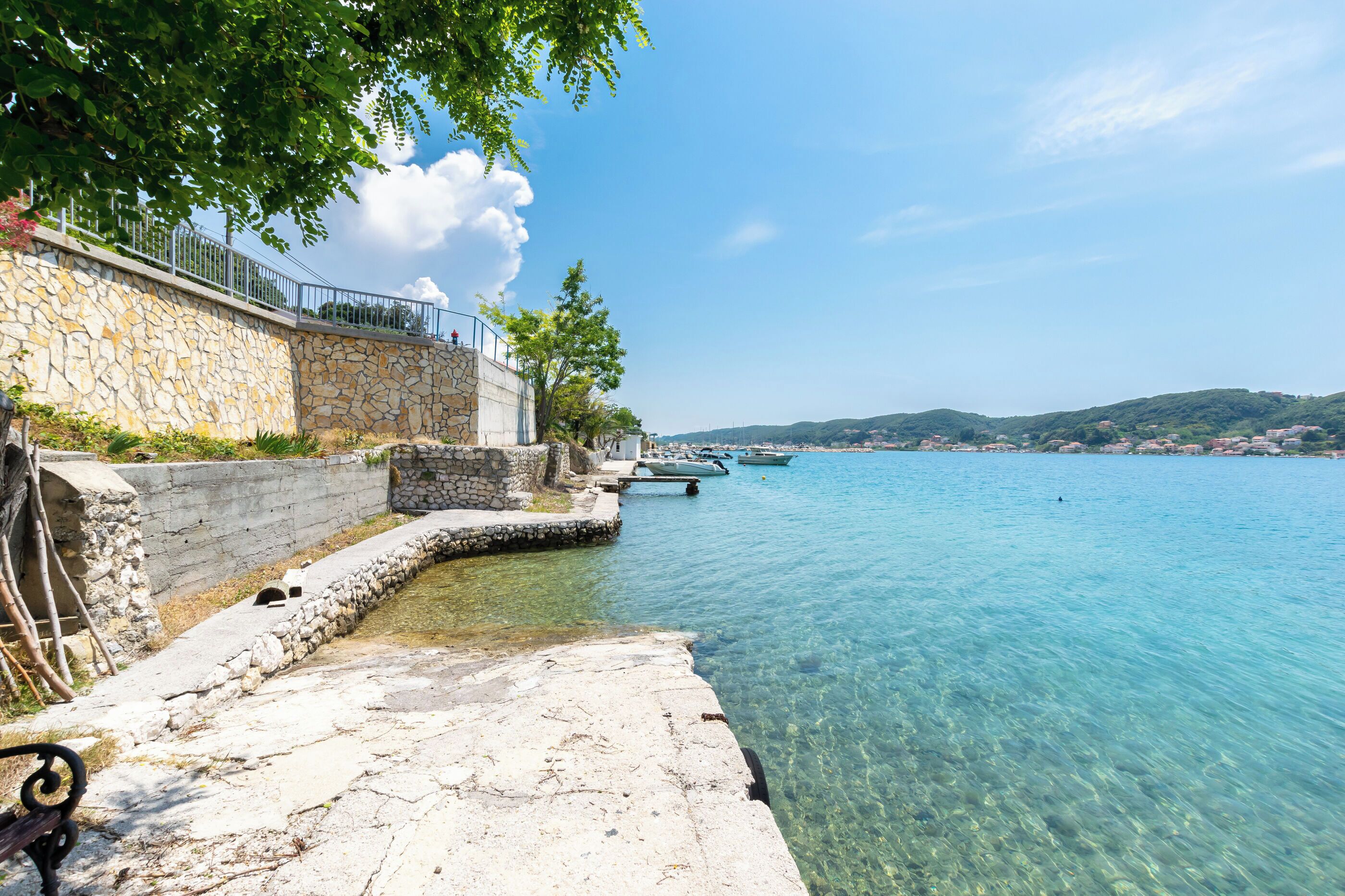 A stone waterfront property with a clear view of the sea and boats.