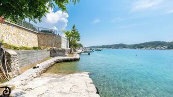 A stone waterfront property with a clear view of the sea and boats.