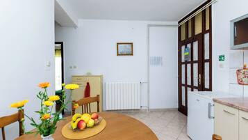 A kitchen with a dining table, a fruit bowl, and a vase of flowers.