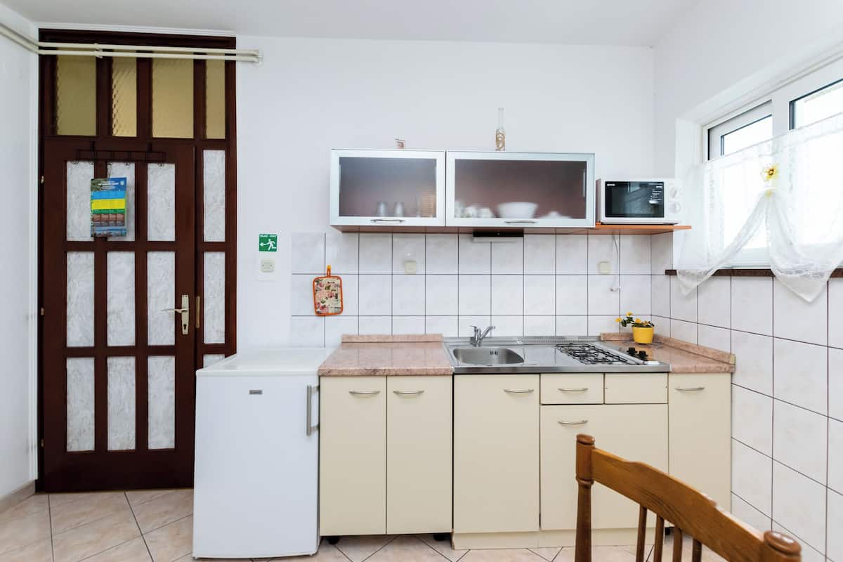 A compact kitchen with a refrigerator, microwave, sink, and cabinets.
