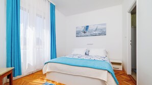 Une chambre à coucher avec un lit, une table de chevet, une fenêtre avec des rideaux et un tableau accroché au mur.