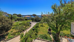 Un quartier résidentiel offrant une vue dégagée sur une maison, un jardin et un chemin menant à un plan d’eau.