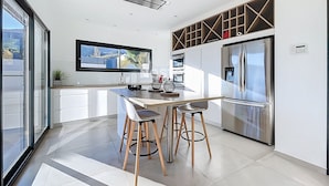 Uma cozinha moderna com uma ilha central, eletrodomésticos de aço inoxidável e uma janela ampla.