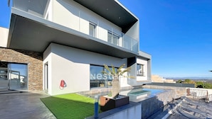 Uma casa moderna de dois andares com telhado plano, janelas amplas e piscina.