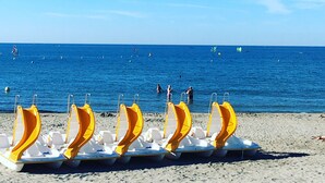 Une plage où plusieurs transats jaunes et blancs sont alignés sur le sable.