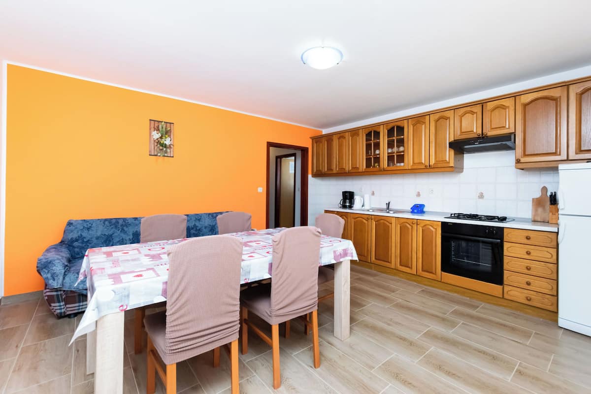 Une cuisine compacte avec des meubles en bois, une table à manger avec des chaises et un petit coin salon avec un canapé.