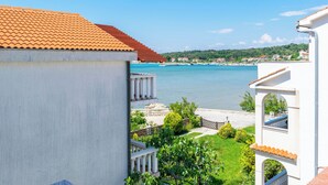 Une vue sur la côte, avec un ciel dégagé, un toit recouvert de tuiles et un balcon donnant sur la mer.