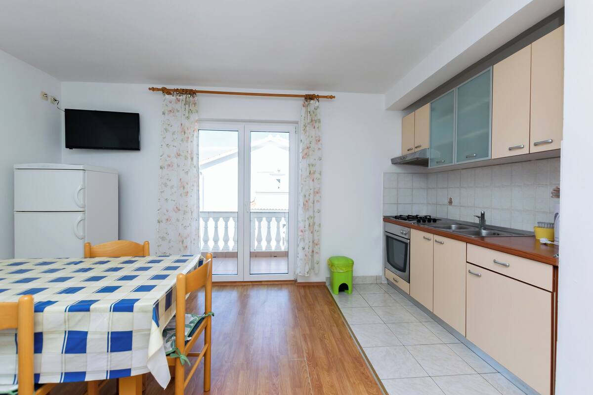 Une cuisine compacte comprenant une table à manger, un réfrigérateur et un téléviseur fixé au mur.